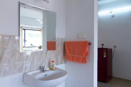 a white bathroom with a sink and a window at Cozy Family Holiday in Madgaon