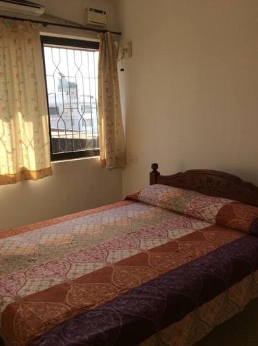 a bedroom with a bed and a window at Cozy Family Holiday in Madgaon