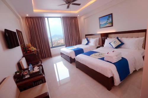 a hotel room with two beds and a window at Blue Wave Hotel in Cửa Lô