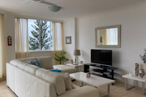 a living room with a white couch and a tv at Ocean Front 2Bed - Unbeatable Views @ Sanderling! in Gold Coast