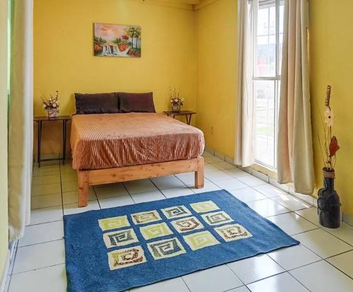 1 dormitorio con cama y alfombra azul en Cómoda Casa 3Hab: Piscina, Seguridad, Parking en Emiliano Zapata