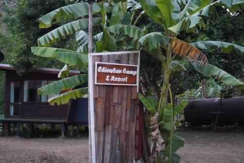 a sign on a wooden pole next to a banana tree at Chiewlan Camp and Resort in Ban Pha Saeng Lang