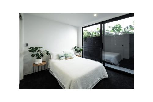 a bedroom with a bed and a large window at Grey Lynn Luxury 4BD Villa w Pool Free Parking in Auckland