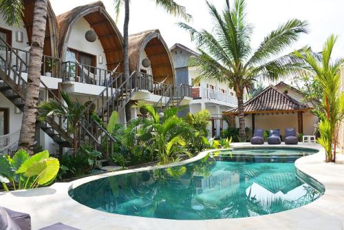 a swimming pool in front of a building with palm trees at My Gili Paradise in Gili Trawangan