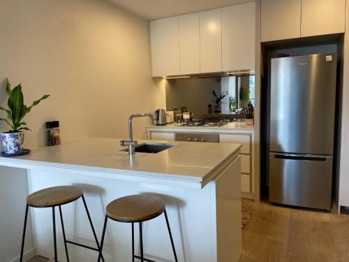 a kitchen with a sink and two bar stools at Perfect City View and gorgeous apartment in Melbourne