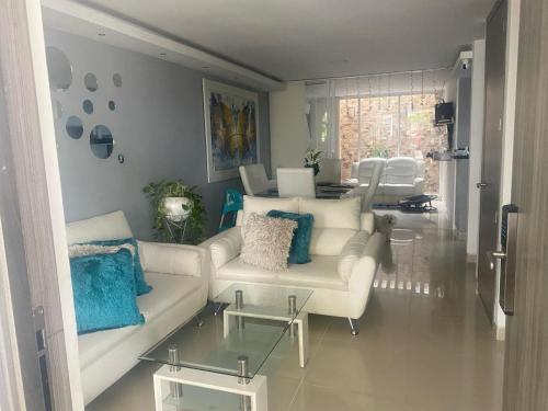 a living room with a white couch and blue pillows at CASA GRANDE 3 CUARTOS 10 PERSONAS in Valledupar