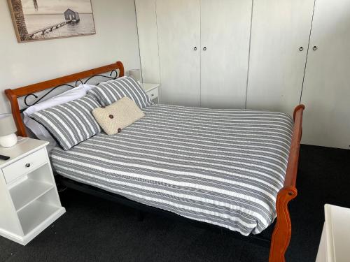 a small bedroom with a bed with a striped blanket at Island Escapes in Alonnah