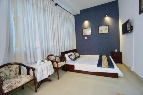 Hotel Hải Châu في Ấp Phước Thọ: غرفة نوم بسرير وطاولة وكراسي