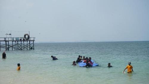 a group of people in the water at the beach at Madu Tiga Beach and Resort in Tanjung Pinang 