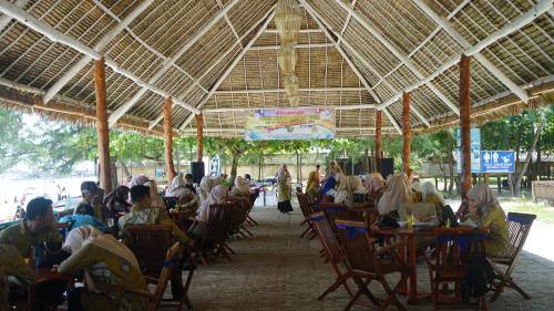 a group of people sitting in chairs under a pavilion at Madu Tiga Beach and Resort in Tanjung Pinang 