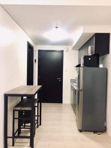 a kitchen with a black door and a table and a refrigerator at Kasara Urban Resort 1BR Condo in Manila