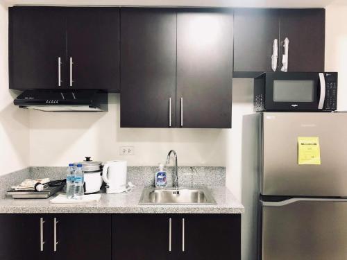 a kitchen with black cabinets and a stainless steel refrigerator at Kasara Urban Resort 1BR Condo in Manila
