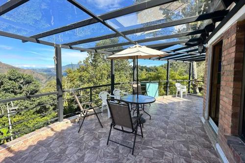 a patio with a table and chairs and an umbrella at Villa Diana, Condominio Oasis in Guayabal de Síquima