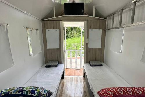two beds in a room with a door with a window at Tiny House On Wheels - Guayabal de Siquima in Guayabal de Síquima