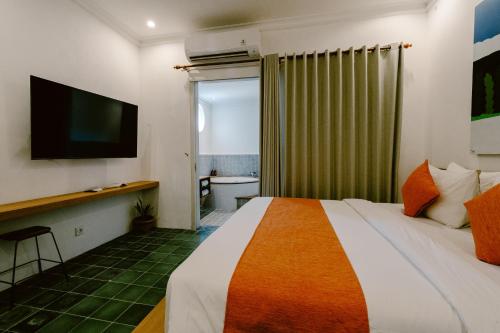 a hotel room with a bed and a television at Brown Feather Hotel in Seminyak
