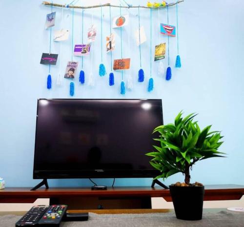 a flat screen tv sitting in a living room with a plant at Vivacity Megamall Jazz Suite 3BR 8pax #Joyoustayz2 in Kuching