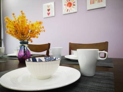 une table avec deux tasses et un vase avec des fleurs dans l'établissement Vivacity Megamall Jazz Suite 3BR 7pax #Joyoustayz, à Kuching