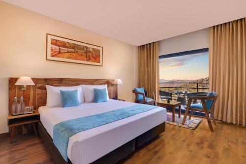 a hotel room with a bed and a desk and a window at Lemon Tree Hotel, Kasauli in Kasauli