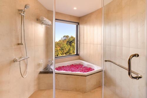 a bathroom with a bath tub with a window at Lemon Tree Hotel, Kasauli in Kasauli