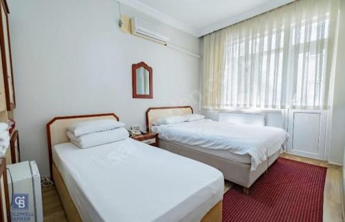sypialnia z 2 łóżkami i oknem w obiekcie AKÇAY LEMAN OTEL w mieście Edremit