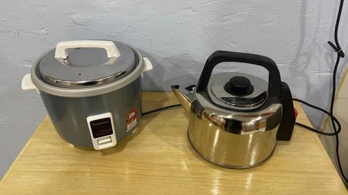 a slow cooker and a tea kettle on a table at Homestay Taman Bahagia in Tenom