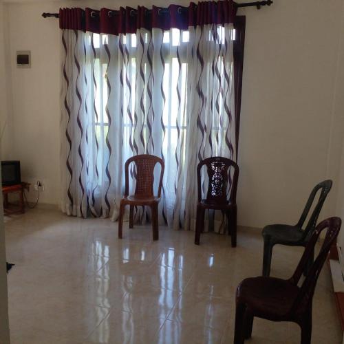 a room with two chairs and a window with curtains at Nora Holiday Home in Diyatalawa