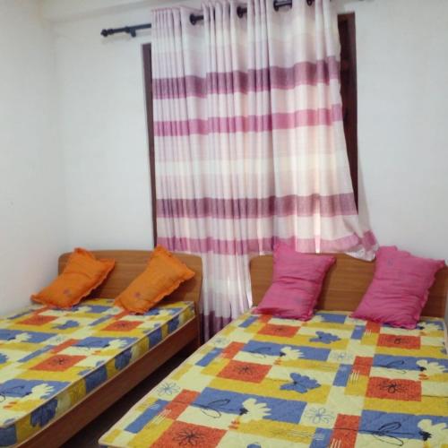 two beds with colorful pillows in a room at Nora Holiday Home in Diyatalawa