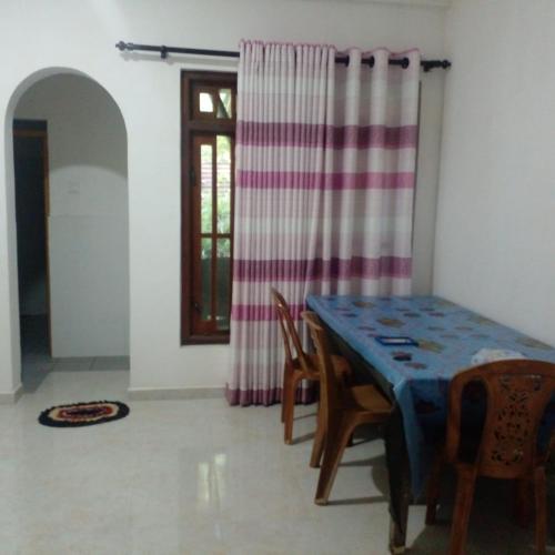 a dining room with a table and chairs and a window at Nora Holiday Home in Diyatalawa