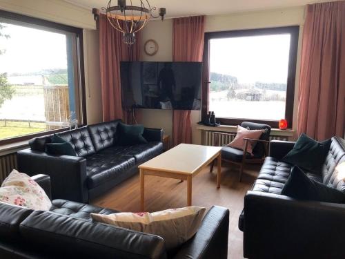 a living room with black leather couches and a tv at Ferienhaus Küstille in Medebach