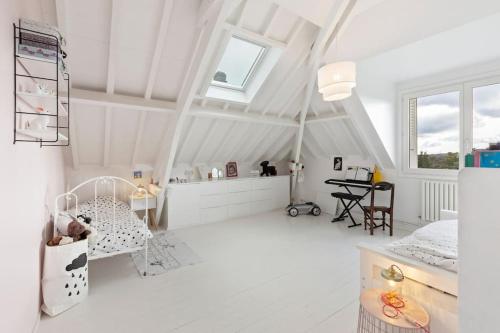 a white attic room with a bed and a table at Grande villa 20 min de Paris centre in Garches