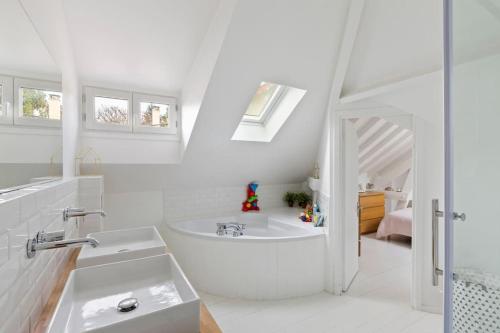 a white bathroom with a tub and a sink at Grande villa 20 min de Paris centre in Garches