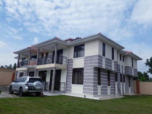 a house with a car parked in front of it at VILLA FIORI APARTMENTS in Arua