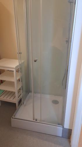 une douche avec une porte en verre à côté d'un tabouret dans l'établissement Les studios d'Eric N6, à Tours