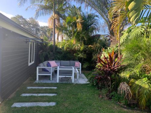 a patio with a table and chairs in a yard at Woy Woy Staycation - Heated Pool & Hot Tub & BBQ & Pizza Oven & Arcade Game & Pool Table in Woy Woy