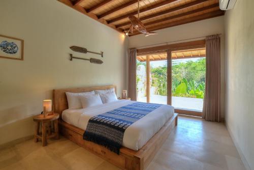 a bedroom with a bed and a large window at Villa Sama Sama 2BR Jungle View in Uluwatu