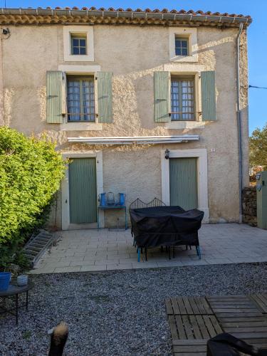 - un bâtiment avec des portes vertes et une table en face dans l'établissement Le Clos des oliviers, à Rieux-en-Val