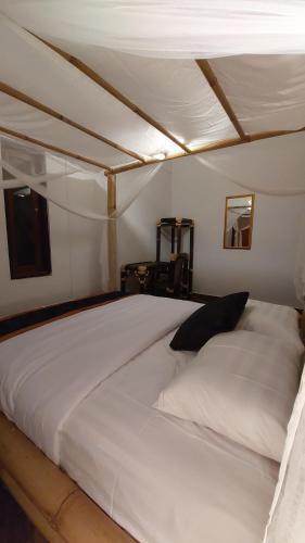 ein großes weißes Bett in einem Zimmer in der Unterkunft Ariwigangga Guest House in Krambitan