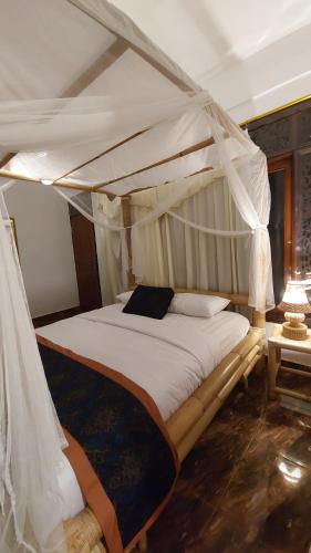 ein Schlafzimmer mit einem Himmelbett in der Unterkunft Ariwigangga Guest House in Krambitan