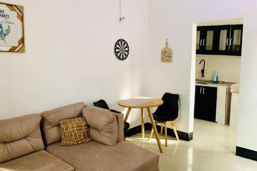 ein Wohnzimmer mit einem Sofa und einem Tisch sowie eine Küche in der Unterkunft Mikocheni Full House - 1 Bedroom in Daressalam