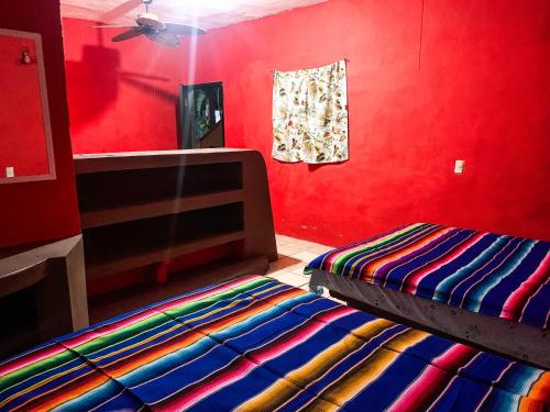 a bedroom with a bed and a red wall at Hostal ROCA INN in Mazatlán