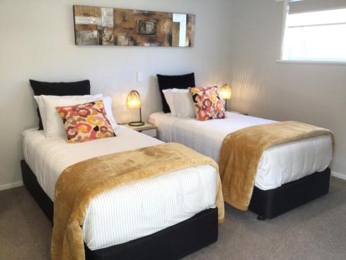 two beds in a room with two lamps at Secret Garden Guest Suite in Tauranga