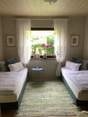 2 Betten in einem Zimmer mit einem Fenster und einem Tisch in der Unterkunft Land und Leute - Landleben Fewo 1 in Fritzlar