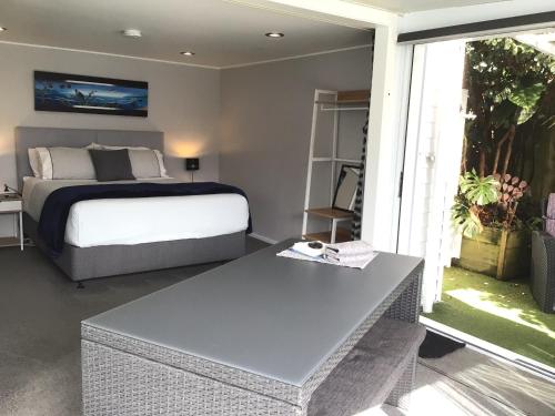 a bedroom with a bed and a table in it at Tranquil Garden Studio in Tauranga