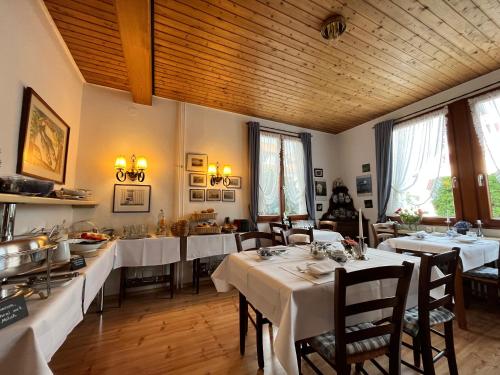 un restaurante con mesas y sillas blancas y ventanas en Hotel Sommerhaus Garni am See, en Bodman-Ludwigshafen
