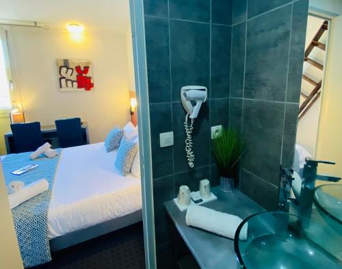 Baño con teléfono en la pared junto a la cama en Hotel & Spa Gil de France Cap d'Agde, en Cap d'Agde