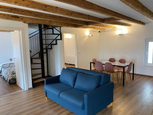 een woonkamer met een blauwe bank en een tafel bij Al FRONTE MARE SUITES APARTMENTS in Muggia