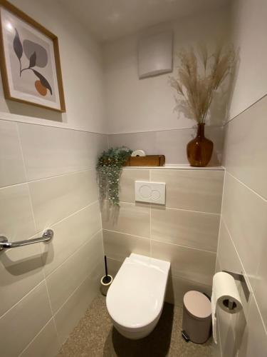 a white bathroom with a toilet and a vase at Appartement Kollingwald in Saalfelden am Steinernen Meer