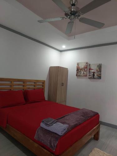 a bedroom with a red bed and a ceiling fan at Vejaleiluc Guest House in Dao