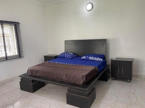 ein Schlafzimmer mit einem Bett mit blauen Kissen darauf in der Unterkunft Royal Diadem Villa in Ile-Ife