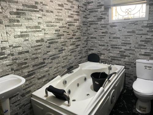 a bathroom with a tub and a toilet and a sink at Royal Diadem Villa in Ile-Ife